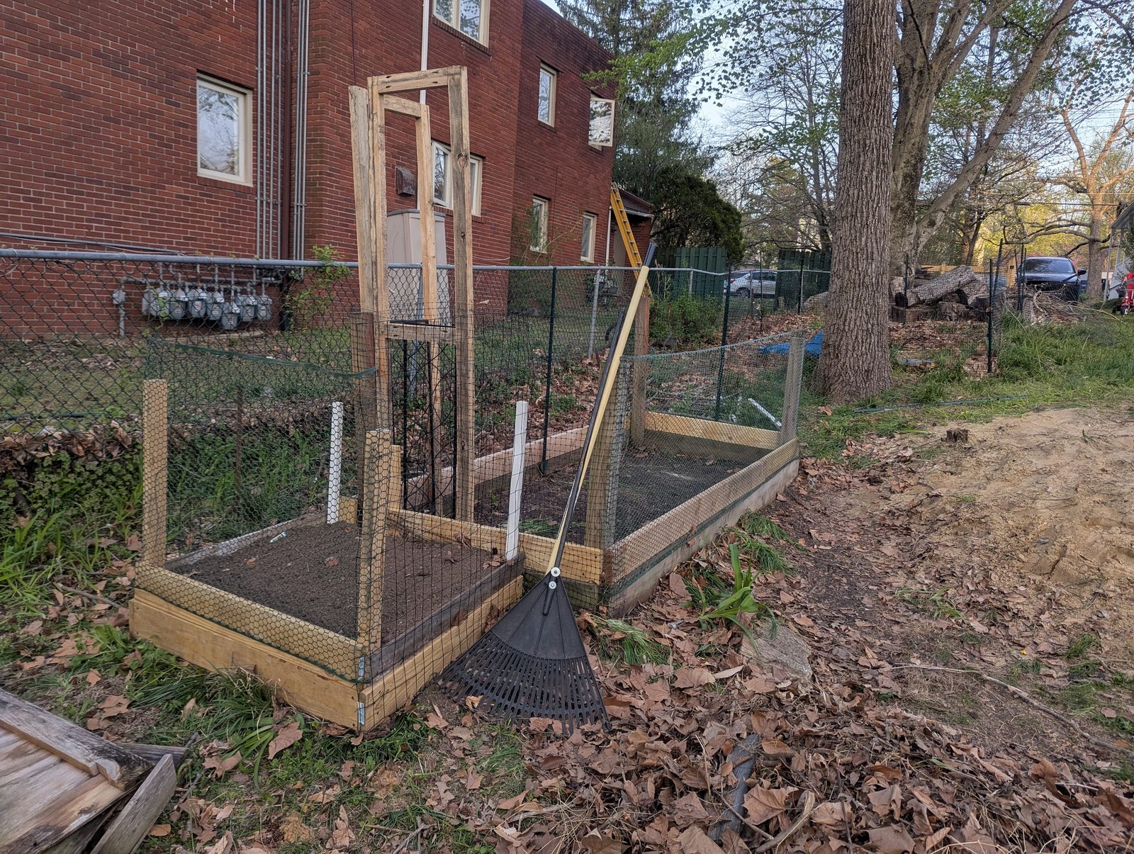 Newly built raised garden bed with wire fencing against a wooded backyard